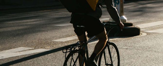 Lieferant auf Fahrrad mit gelbem Rucksack